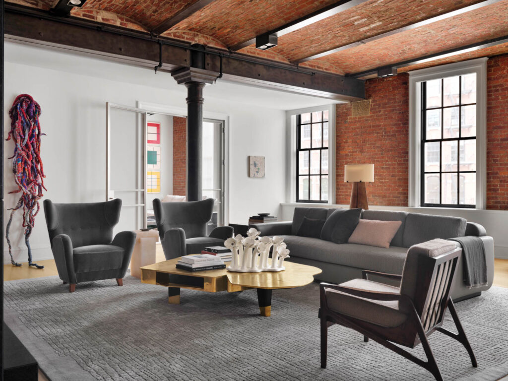 sitting room with dark black couch and chairs and the exposed red brick wall in the background