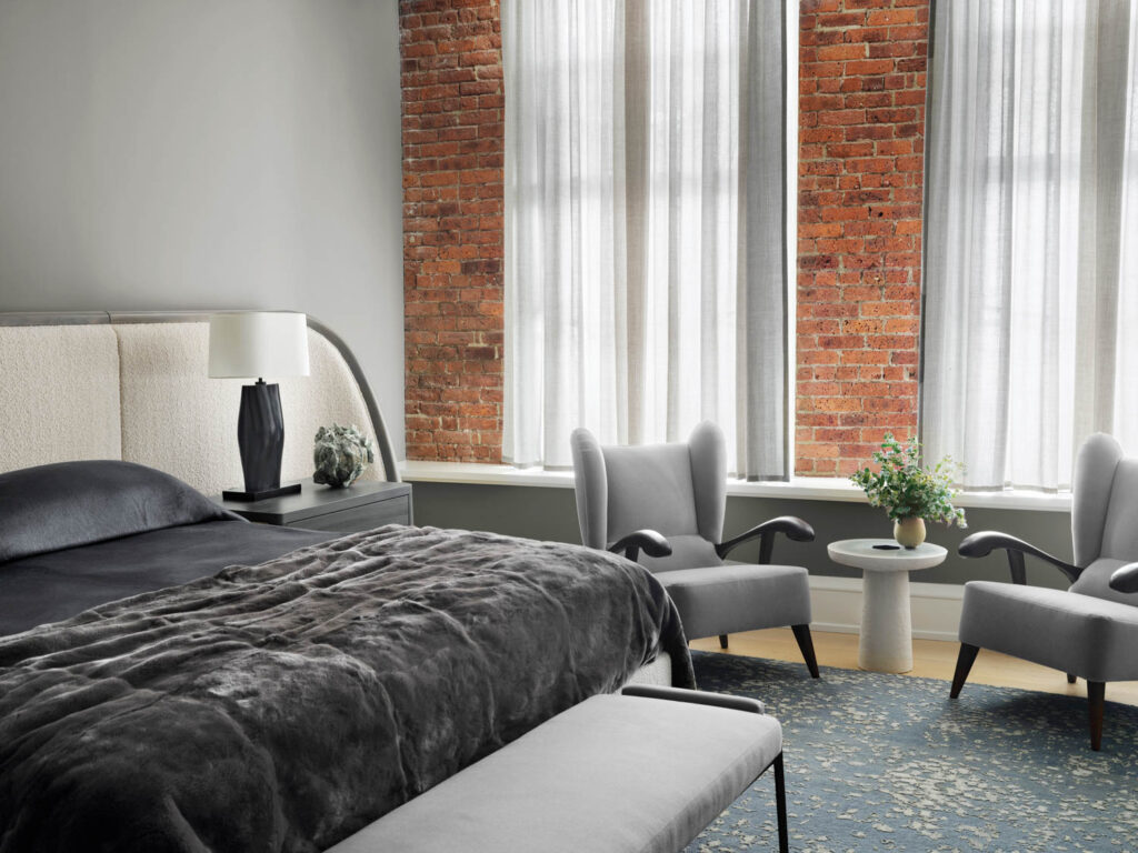 bedroom with bed with black sheets, reading nook and white drapes