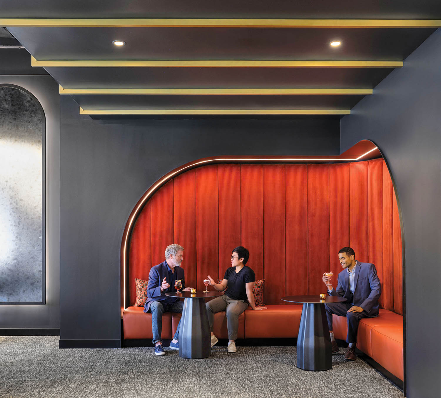 corner of office space with red booth and black walls