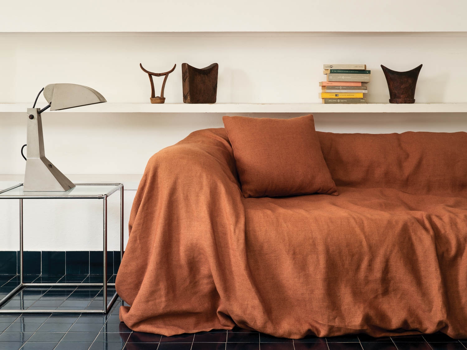 rust colored daybed in front of a white shelf with knickknacks
