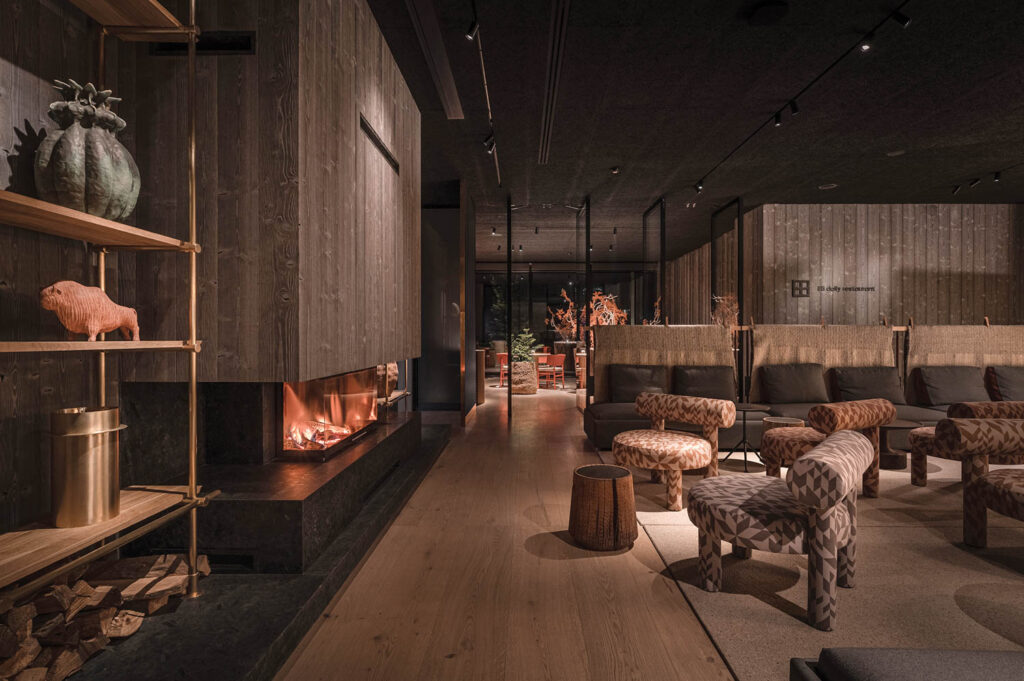 dark moody lounge with multiple chairs and shelves surrounding a fireplace