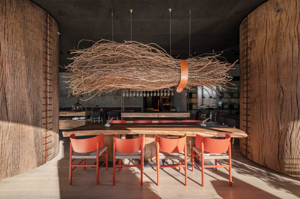 dining room with broom-like chandelier over a dining table with orange chairs