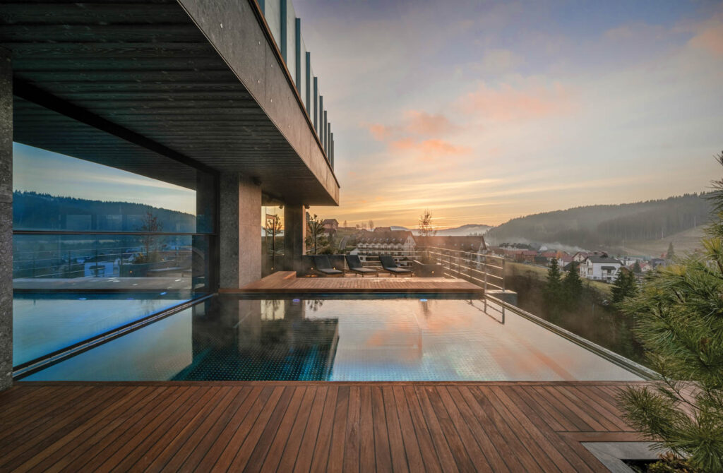 outdoor hotel pool with a view of the sunset and the surrounding landscape