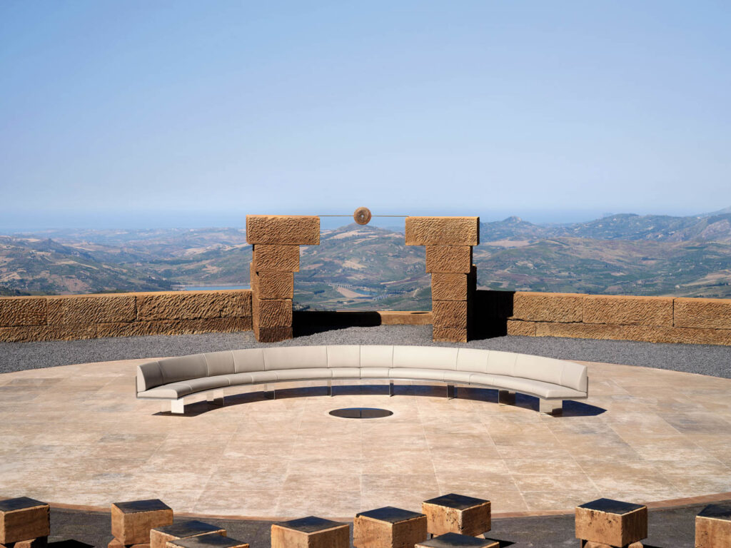 aerial view of a curved couch on a tile platform overlooking the mountains