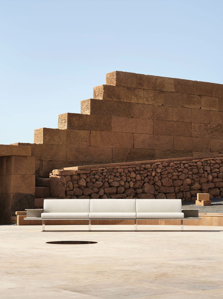 long white couch in front of a large brick wall