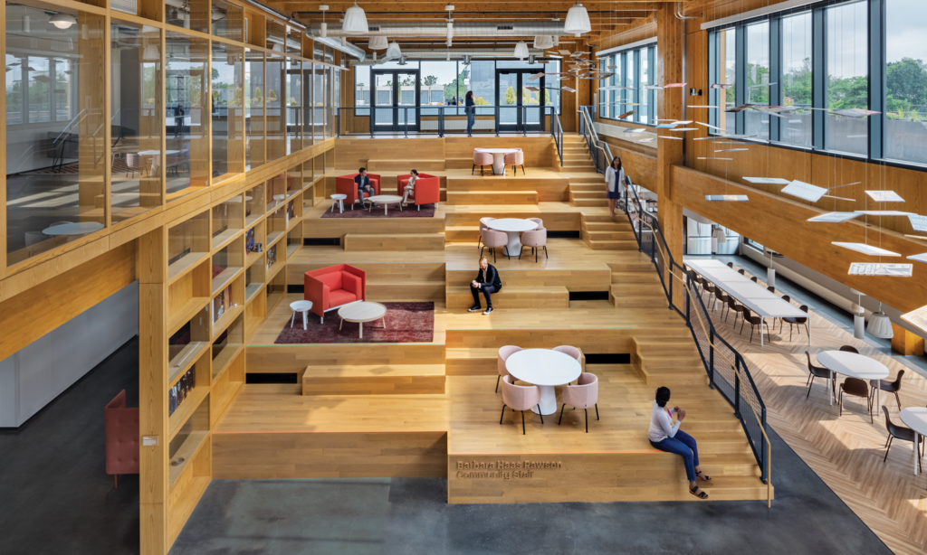 large communal space with people sitting on top of wooden platforms with windows all around